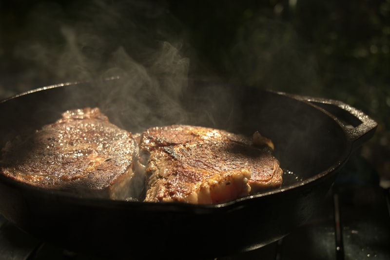 Butter and herbs basting a steak in a tilted cast iron pan