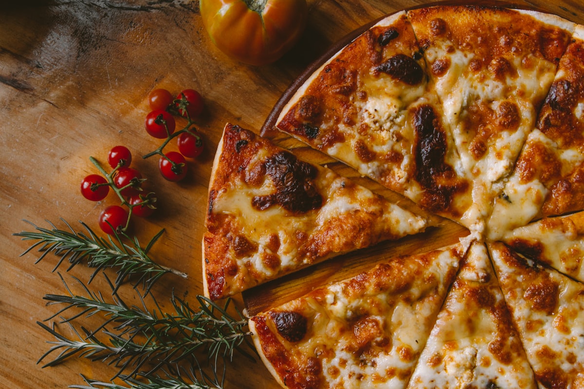 Fresh pizza with melted cheese and basil on a wooden peel