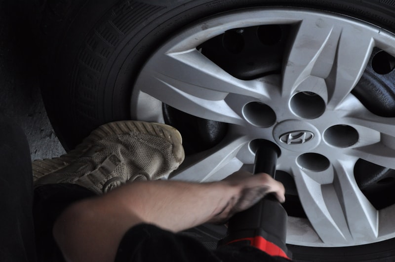 Person removing a flat tire from a car wheel hub
