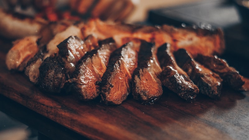 Sliced steak resting on a wooden cutting board with fresh herbs